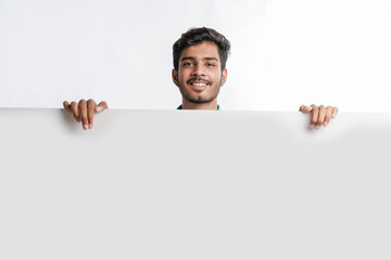 Indian man holding white board, promoting offers on festival season while wearing traditional cloths, standing over white background.