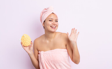 Wall Mural - hispanic pretty woman smiling happily, waving hand, welcoming and greeting you. bathrobe and sponge concept