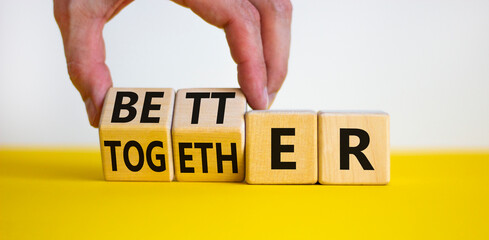 Wall Mural - Better together symbol. Businessman turns cubes and changes the word together to better. Beautiful yellow table, white background, copy space. Business, motivational and better together concept.