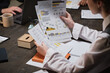 © AnnaStills - Young businesswoman sitting at the table and examining financial documents during business meeting at office