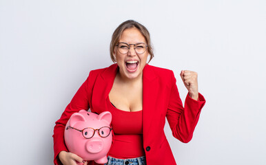 Wall Mural - hispanic pretty woman shouting aggressively with an angry expression. piggy bank concept