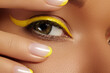 © marinafrost - Close-up Female Eye with bright yellow Eyeliner Makeup. Neon Disco make-up and Fashion Manicure. Summer beauty style