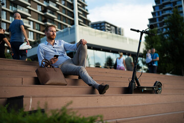  Businessman using the phone while sitting on the stairs. Happy man using the phone.
