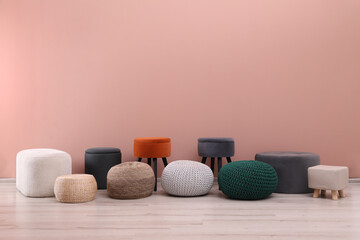 Different stylish poufs and ottomans near pink wall, space for text