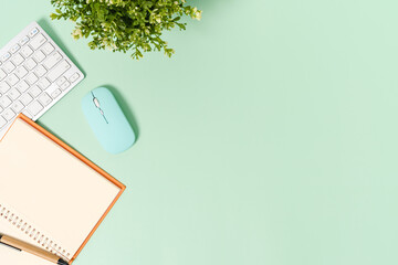 Creative flat lay photo of workspace desk. Top view office desk with keyboard, mouse and open mockup black notebook on pastel green color background. Top view mock up with copy space photography.