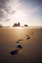 Footprints In Sand On Beach Leading To Sea. Golden Sunset In Tenerife, Canary Islands, Spain..