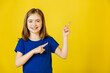 © Alexandr - Wow look, advertise here Portrait of satisfied cute little girl with blue t-shirt pointing to empty place on yellow background, showing copy space for promotional ad. studio shot
