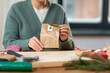 © Syda Productions - christmas, winter holidays and hobby concept - close up of woman with clothespin, craft paper bag and tag packing gift and making advent calendar at home
