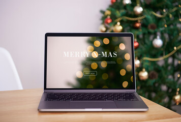 Wall Mural - Mock up laptop computer on office table with Christmas tree and ornaments background.