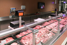 Refrigerated Display Case With Pieces Of Fresh Raw Red Meat At The Butcher In Supermarket