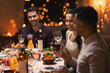 © Syda Productions - holidays, party and celebration concept - multiethnic group of happy friends having christmas dinner at home and drinking wine