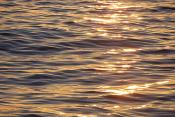 Water surface with small waves. Soft lines, sun glare at dawn. Blue, purple, orange. Abstract natural background