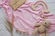 © IndrePau - Pregnancy announcement background, expecting a baby girl concept, flat lay composition on pink blanket with boho rainbow decoration and soft toy bear.