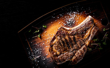 Sticker - Grilled Ribeye Steak on bones on wooden board, prime cowboy steak on dark background