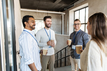 Poster - business, people and corporate concept - happy smiling colleagues with name tags drinking takeaway coffee at office