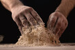 Cooking, kneading dough. Male hands mix the ingredients for the dough on the table against a dark background.