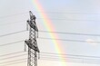 Electricity pylons with rainbow in background, global energy crisis, renewable energy and grid stability concept