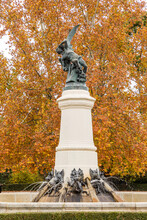 Sculpture Of The Fallen Angel Or Devil In Retiro Park With Trees In Autumn Colors