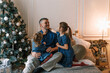 © Tatsiana - Dad and little daughters have fun together, sitting on the bed surrounded by pillows near the Christmas tree. happy christmas