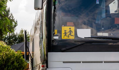 Single empty modern school trip bus, kids transport designated coach vehicle detail, closeup, nobody, frontal shot. Children journey safety concept. Traffic, transportation, means of transport