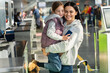 © NFstock - Waist up portrait view of the overjoyed mother and daughter embracing with each other after giving documents to airport worker