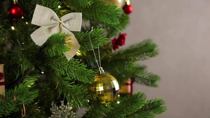 Wall Mural - Girl hangs a golden christmas ball on the tree. 