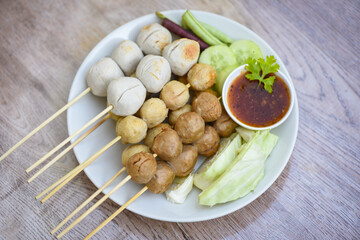 Wall Mural - Meatballs on skewers on white plate and fresh vegetables cabbage yard long bean cucumber, Asian Thai food grilled meatballs fishball and porkball with picy sauce