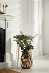 Sticker - Beautiful eucalyptus branches in vase and stool near fireplace indoors