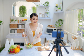 Wall Mural - Asian beautiful woman  recording her cooking video using a mobile phone.