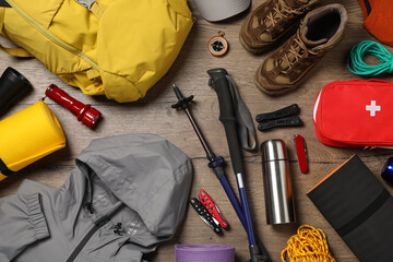 Flat lay composition with trekking poles and other hiking equipment on wooden background