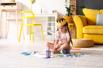 Wall Mural - Cute little girl in paper crown painting on floor at home