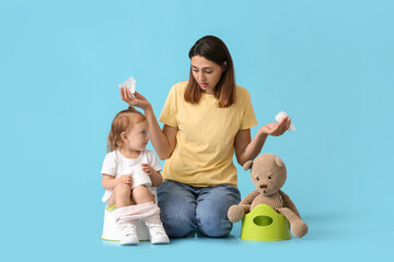 Wall Mural - Mother potty training her little daughter on color background