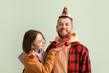 Wall Mural - Happy young couple in stylish winter clothes and with Christmas decor on light background