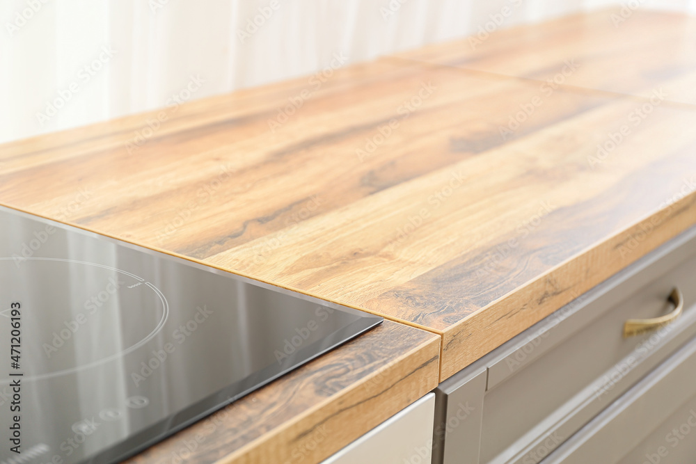 Wooden table top with stove in modern kitchen, closeup