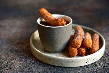 Wall Mural - Traditional spanish dessert churros - fried choux pastry with chocolate sauce on a plate .