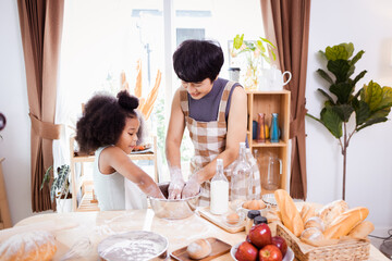 Happy African American mother and daughter having fun while preparing cookie dough at home. happy family time.