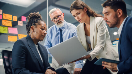 Wall Mural - In Modern Office: Diverse Team of Managers Use Laptop and Tablet Computers at a Company Meeting Discussing Business Projects. Young, Motivated and Experienced Employees Brainstorm in Conference Room.