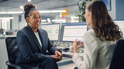 Poster - Two Female Colleagues Fondly Talk to Each Other, Laugh and Smile while Working on Computers in Diverse Modern Business Office. Experienced Manager and Young Employee Discuss a Fun Analytical Project.