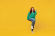 Full size body length happy vivid young ginger chubby overweight woman 20s wears green shirt doing winner gesture celebrate clenching fists say yes isolated on plain yellow background studio portrait.