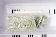 Frozen green pea in bags in freezer close-up, front view