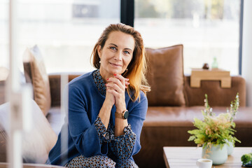 Serious woman sitting with clasped hands looking at camera