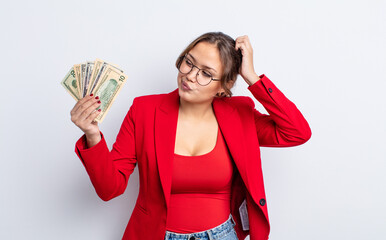 Wall Mural - hispanic pretty woman smiling happily and daydreaming or doubting. business and banknotes concept