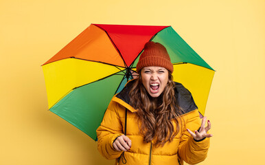 Wall Mural - hispanic pretty woman looking angry, annoyed and frustrated. umbrella concept