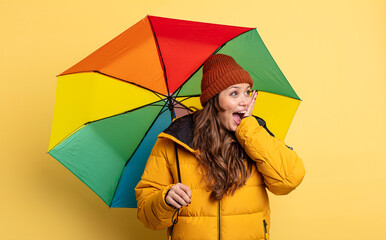 Wall Mural - hispanic pretty woman feeling happy, excited and surprised. umbrella concept