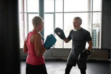 Senior man and woman boxing in gym