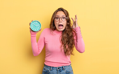 Wall Mural - hispanic pretty woman screaming with hands up in the air. alarm clock concept