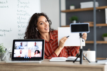 Wall Mural - Young teacher having video conference using cellphone and pc