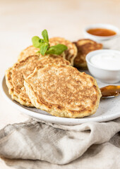 Wall Mural - Tasty oatmeal pancakes served with jam and natural yogurt on ceramic plate, light concrete background.