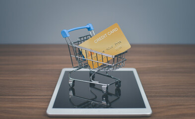 Credit card is placed in the shopping cart placed on the tablet device in the concept of online shopping with credit card.