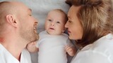 Fototapeta  - Happy parents with his newborn baby, top view. Happy family. Healthy newborn baby with mom and dad. Close up Faces of the mother, father and infant baby. Cute Infant boy and parents.
